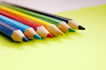 Colored pencils on yellow background. Lots of different colored pencils. Colorful pencil. Close-up. Pencils are sharp. Pencils lie diagonally in the top left corner. Copy space. Background. Fiat lay