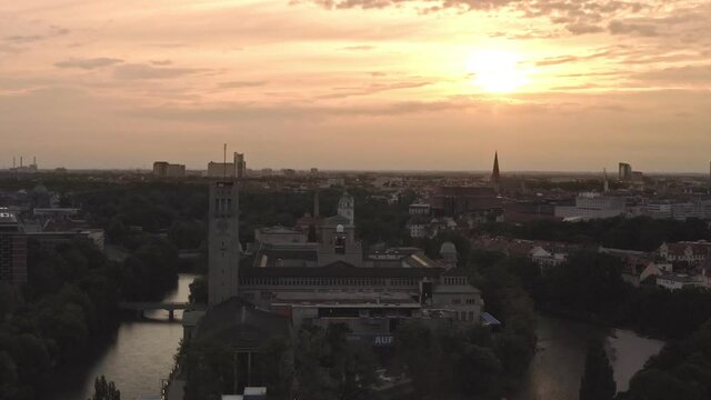 Colorful oranage sunrise view over Munich by flying backwards with the drone - 4K beauty shot of the inner bavarian city in germany.