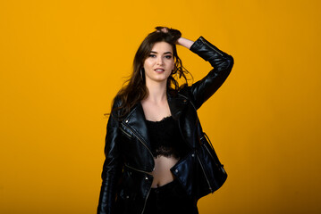 Portrait of a happy young brunette girl showing gestures and smiling, surprising isolated over yellow background. Emotional picture.