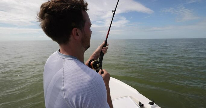 Man fishing in the sea from boat casting bait throwing line.