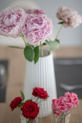 Pink peonies and red roses flower bouquets on pot and glasses on an indoor decoration scene