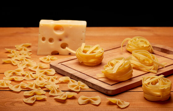 Raw pasta and cheese on a wooden table, healthy food concept