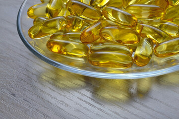 Fish oil capsules on a glass plate. A lot of vitamin omega 3. Close-up.
