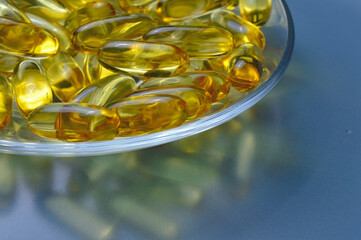 Fish oil capsules on a glass plate. A lot of vitamin omega 3. Close-up.