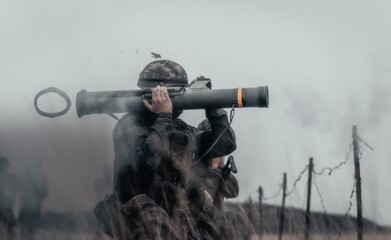 Closeup shot of a soldier in a field firing bazooka