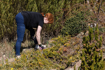 The red-haired woman lifts the cut dry grass onto a pile of straw deposited on the lawn.