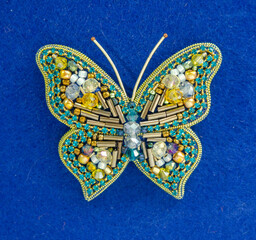 Fototapeta na wymiar Golden Butterfly from beads and rhinestones, brooch on a blue background