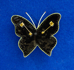 Golden Butterfly from beads and rhinestones, brooch on a blue background