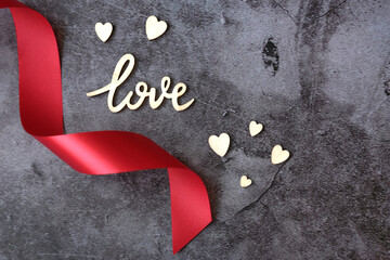 Wooden love and hearts with red ribbon on marble gray background