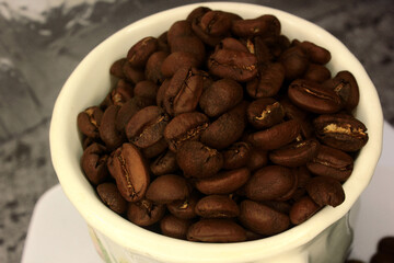 photo of coffee beans that are ready to be ground in a cup, illustrating the freshness of the coffee to be processed, coffee is a popular caffeine supplement consumed by many people