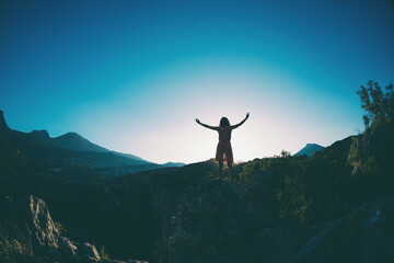 A girl in a dress stands on top of a mountain, a woman looks at a mountain valley