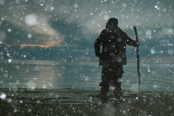 Naklejka premium traveler with a stick walking along the lake at night