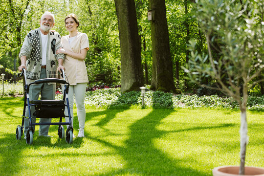 Senior man with helpful volunteer in the garden of professional care home