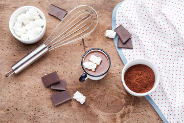 Metal mug of hot chocolate with marshmallows on wooden background.