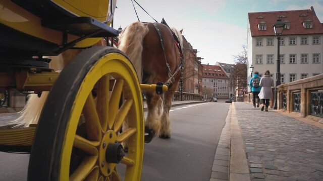 Old yellow stagecoach with horses rides on the streets of old town