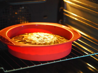 Homemade baking in the kitchen oven.Apple pie in a gel red baking dish.