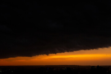 Black thunderclouds at sunset. Bright orange sunset and dark clouds. Storm sky