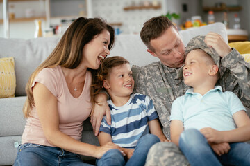 Happy soldier sitting on the couch with his family. Soldier and his wife enjoying at home with children.