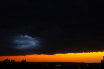Black thunderclouds at sunset. Bright orange sunset and dark clouds. Storm sky