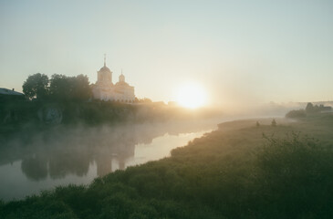 Church at foggy dawn. Fog on the river.