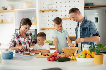 Mother and father making breakfast with sons. Young family preparing delicious food in kitchen.