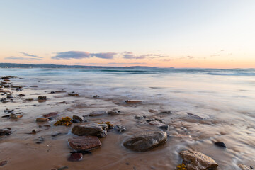 Water flowing around the rocks on the sand.