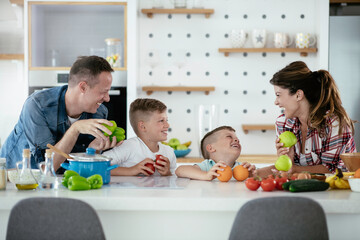 Mother and father making breakfast with sons. Young family preparing delicious food in kitchen.