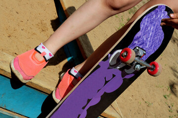Girl in pink sneakers and a skateboard.
