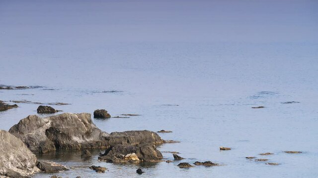 Blue sea water with stone rocky shore at cloudy sunless day. Spanish coast nature. Mediterranean Sea