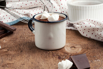 Metal mug of hot chocolate with marshmallows on wooden background.