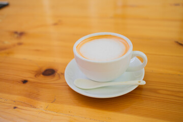 Hand Women put a Latte arts coffe hot coffee on wooden table.barista love art concept.