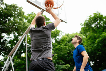 Two young men playing basketball in the park. Friends having a friendly match outdoors