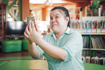 Asian young blind person woman disabled people taking selfie or video call using smart phone in creative workplace