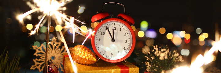 Red alarm clock with christmas gifts against night city background. Happy New Year concept