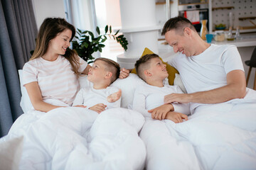 Obraz premium Beautiful parents with kids enjoying at home. Young family watching movie on lap top.