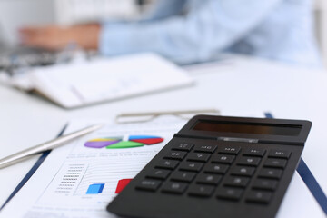 The black calculator lies on a chessboard. Background for calculating the business strategy calculation.