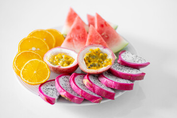 White plate of sliced fruit. Fresh fruits and vitamins. Still life colored summer fruits.