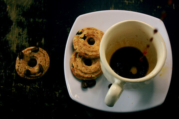 the process of pouring espresso on a white ceramic mug with some diet biscuits, suitable for coffee connoisseurs who don't want to consume a lot of calories from regular biscuits