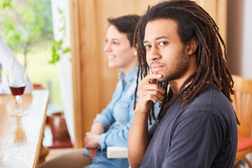 Afrikaner mit Dreadlocks sitzt mit Freunden am Tisch