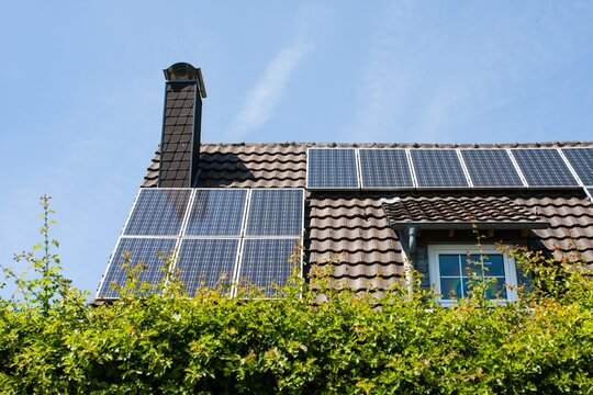 Home with chimney and brown roof with black rectangular solar panels