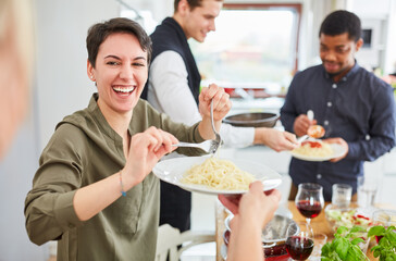 Junge Frau serviert Nudeln mit Tomatensauce in WG