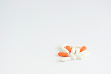 A small pile of tablets, capsules, pills lies on a white background. Place for text