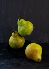 selective focus: large ripe pears with water drops on a dark background
