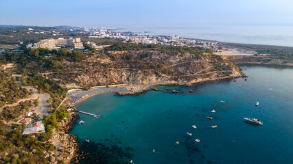 Fototapeta na wymiar Aerial bird's eye view of Konnos beach, Cavo Greco Protaras, Paralimni, Famagusta, Cyprus. Famous tourist attraction golden sandy bay with boats, yachts in the sea, sunbeds, water sports, from above.