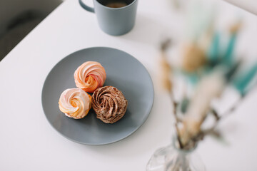 Cup of coffee with marshmallows and flowers on the table. Romantic morning. Tasty breakfast. Flat lay, top view, copy space.