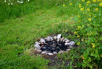 extinguished fireplace in the garden in a flowery meadow lined with limestone stones flowering...