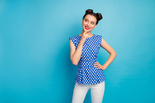 Photo of wondered intelligent pretty lady look dreamy empty space thinking about creative idea red lips wear dotted blouse white trousers isolated blue color background