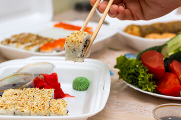 sushi and rolls with home delivery, eat at the table against the background of food