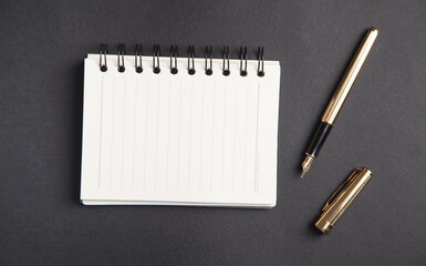 Pen and notepad on black background.