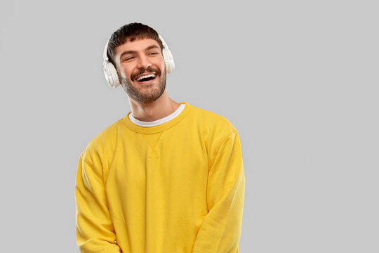 music, technology and people concept - happy smiling young man in headphones over grey background